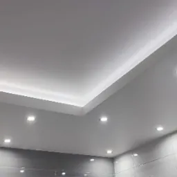 Nowoczesna łazienka z podwieszanym sufitem z oświetleniem LED i punktowymi lampami, szare płytki na ścianach.