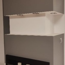 Look home remonty i instalacje - Szara ściana z wnęką na świece i półkami, minimalistyczny design, wykończenie wnętrza.