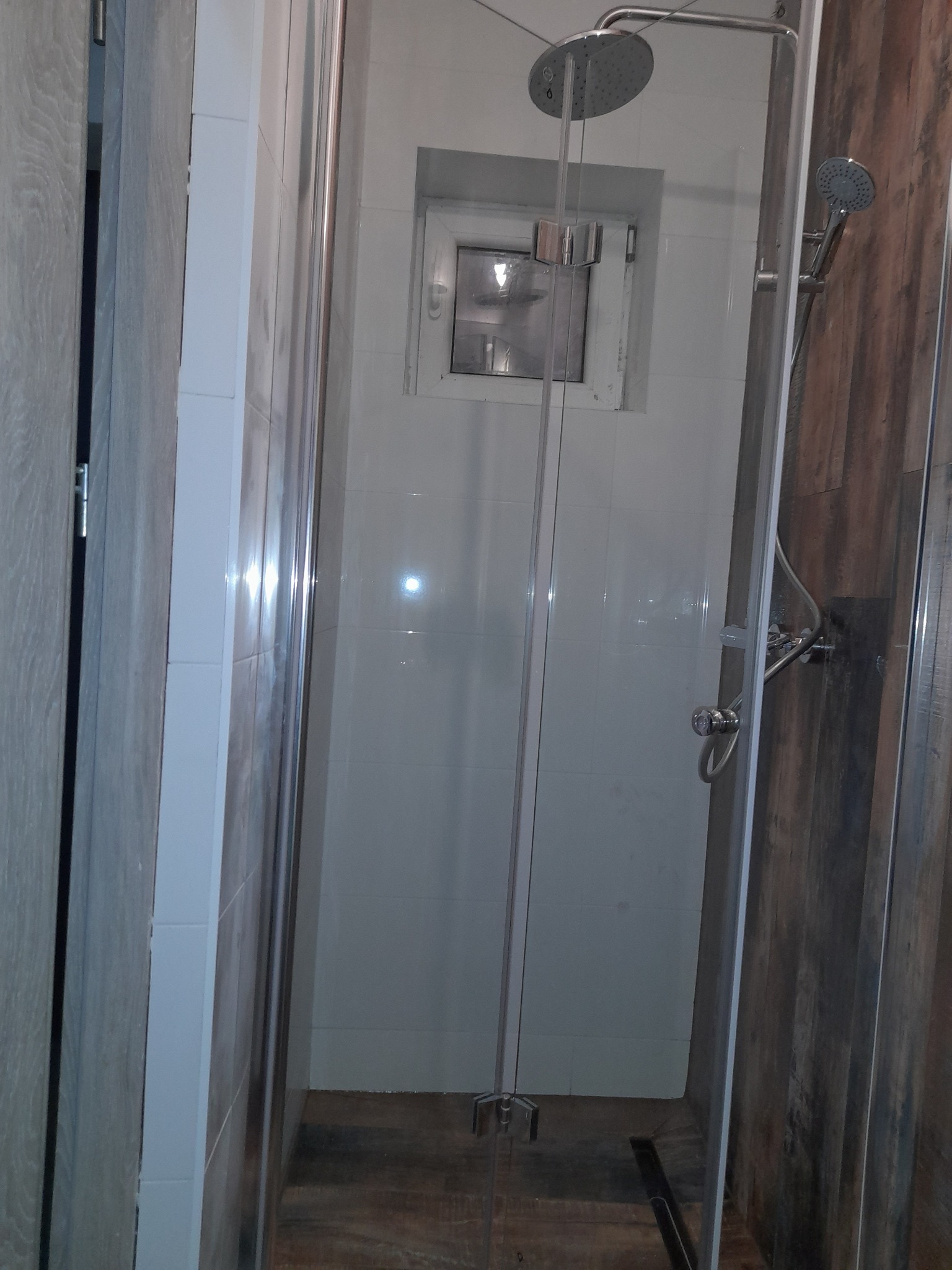 Kabina prysznicowa z deszczownicą i odpływem liniowym w łazience w Rudniku, wykończona płytkami imitującymi drewno.