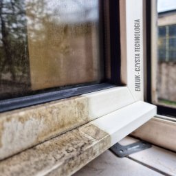Klein - Częściowo umyte okno PCV, widoczna różnica między brudną i czystą ramą okienną, napis 'EMLUK - CZYSTA TECHNOLOGIA' na boku ramy.