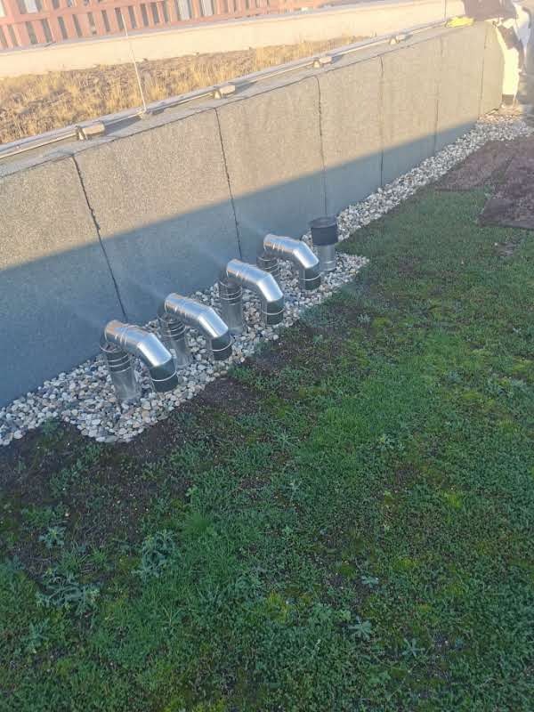 Zielony dach z systemem wentylacyjnym i kamieniami drenażowymi wzdłuż ściany attykowej.