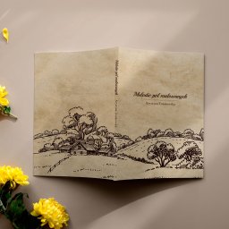 Varietatis - Otwarta książka z ilustracją krajobrazu wiejskiego w stylu retro, leżąca na beżowym tle z żółtymi kwiatami chryzantemy po lewej stronie.
