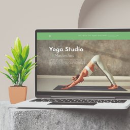 Varietatis - Laptop wyświetla stronę internetową studia jogi z kobietą wykonującą pozycję psa z głową w dół, obok stoi roślina w doniczce na betonowym bloku.