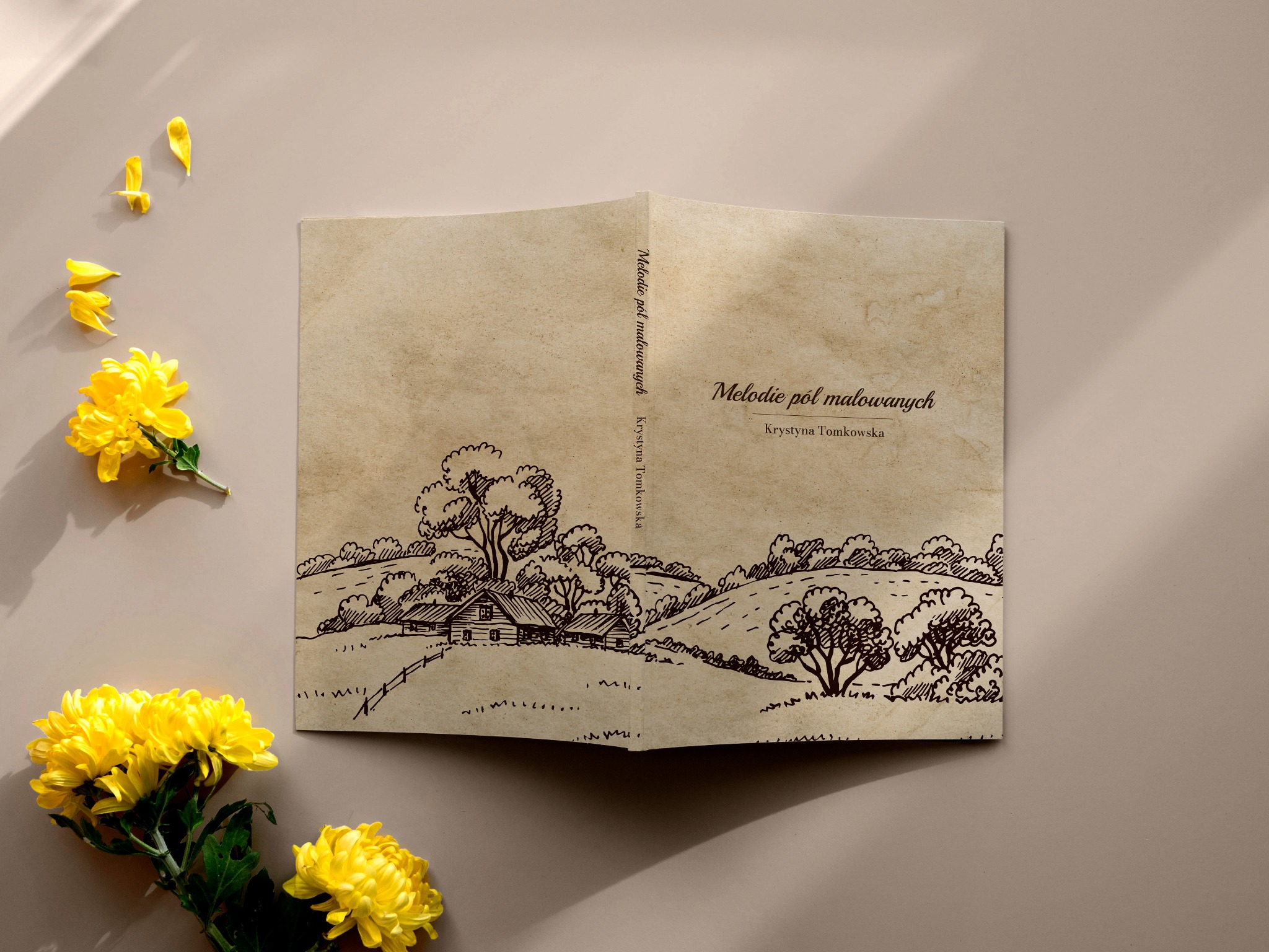 Otwarta książka z ilustracją krajobrazu wiejskiego w stylu retro, leżąca na beżowym tle z żółtymi kwiatami chryzantemy po lewej stronie.