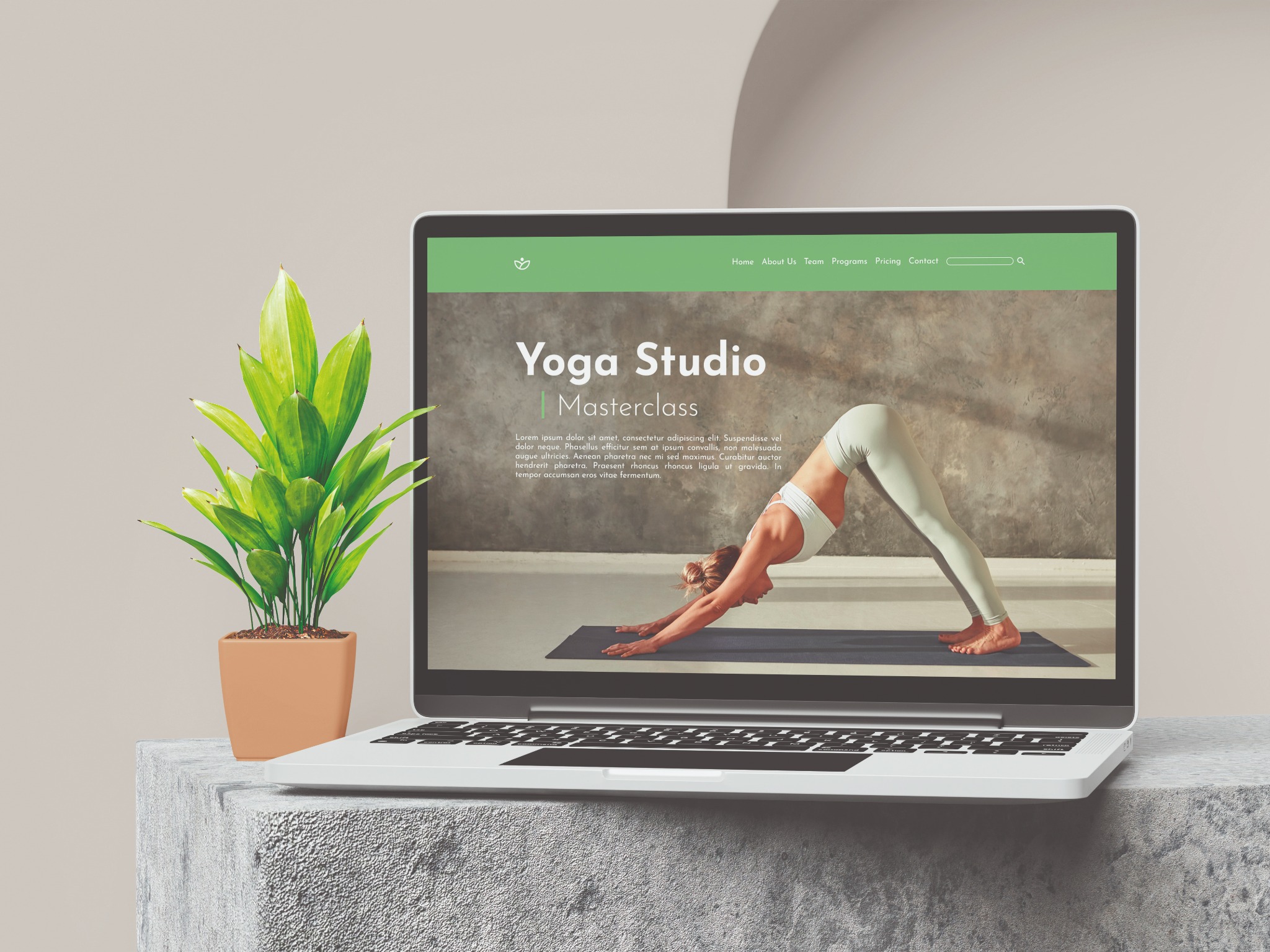 Laptop wyświetla stronę internetową studia jogi z kobietą wykonującą pozycję psa z głową w dół, obok stoi roślina w doniczce na betonowym bloku.