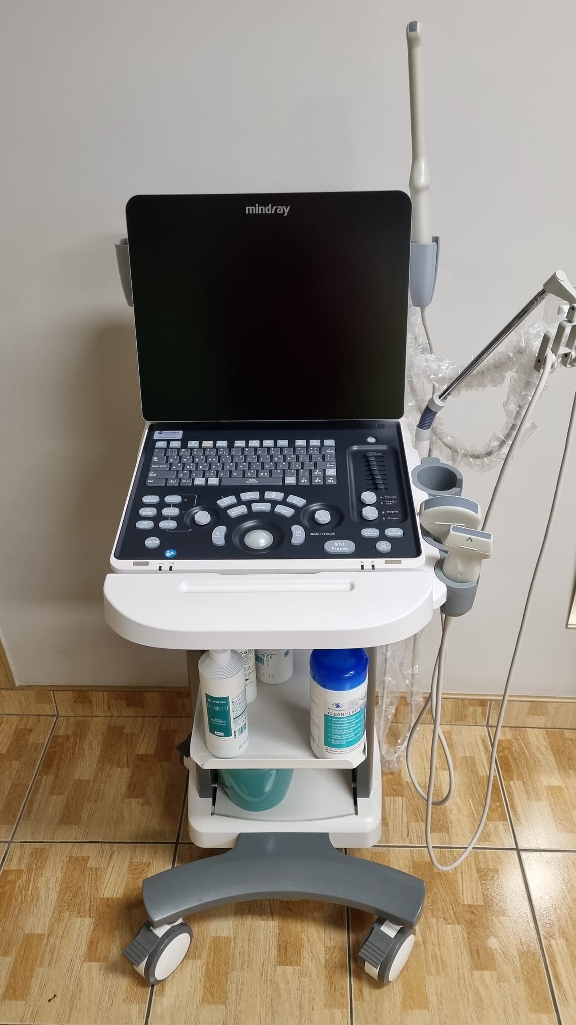 Aparat USG marki Mindray na wózku z półkami, na których znajdują się środki do dezynfekcji.