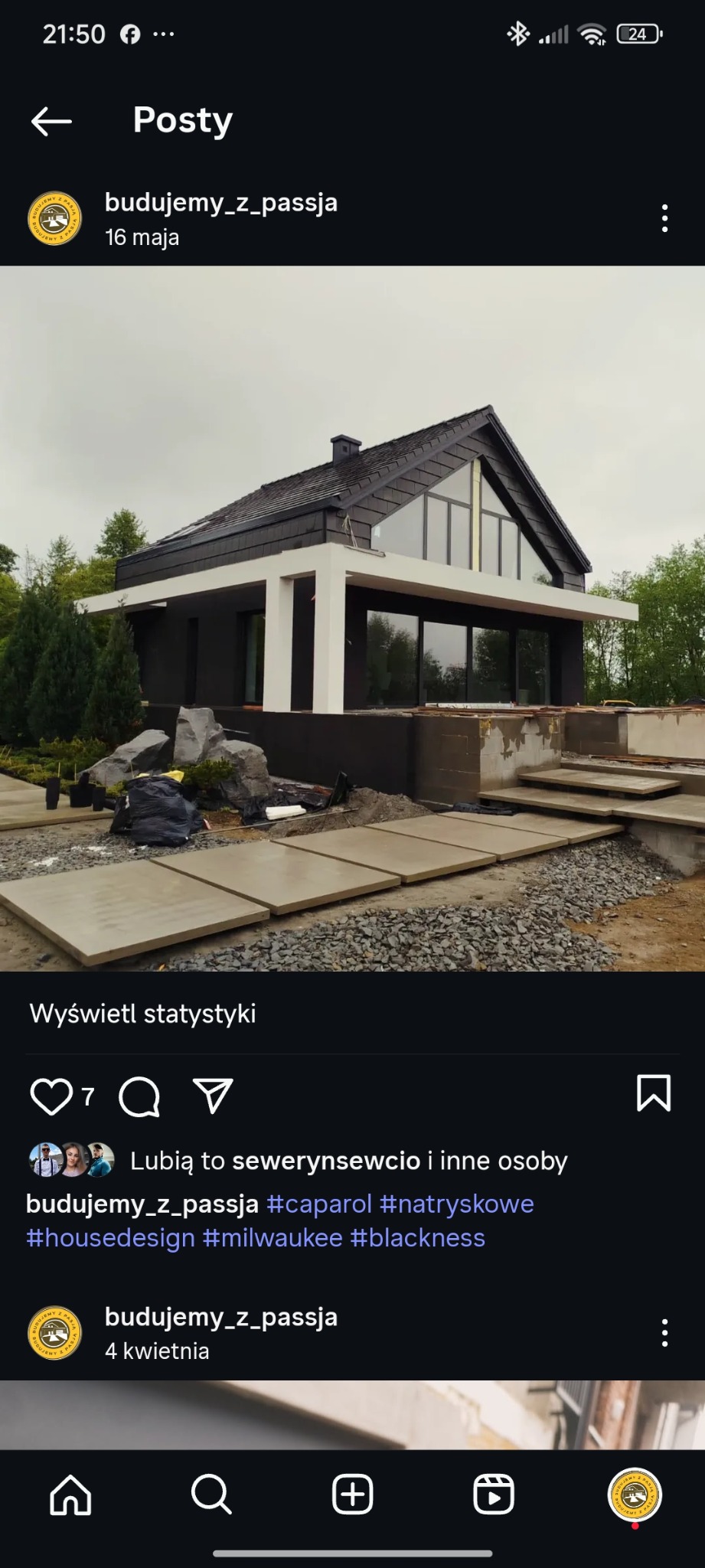 Nowoczesny dom z czarną elewacją i dachem, jasnymi elementami konstrukcyjnymi. Widoczne schody wejściowe i elementy krajobrazu.