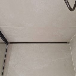 Andrii Maksymovych Ander-mar BUD - Beżowe płytki w kabinie prysznicowej z odpływem liniowym i deszczownicą w Świdnicy. Minimalistyczny design, neutralna kolorystyka, widok z góry.