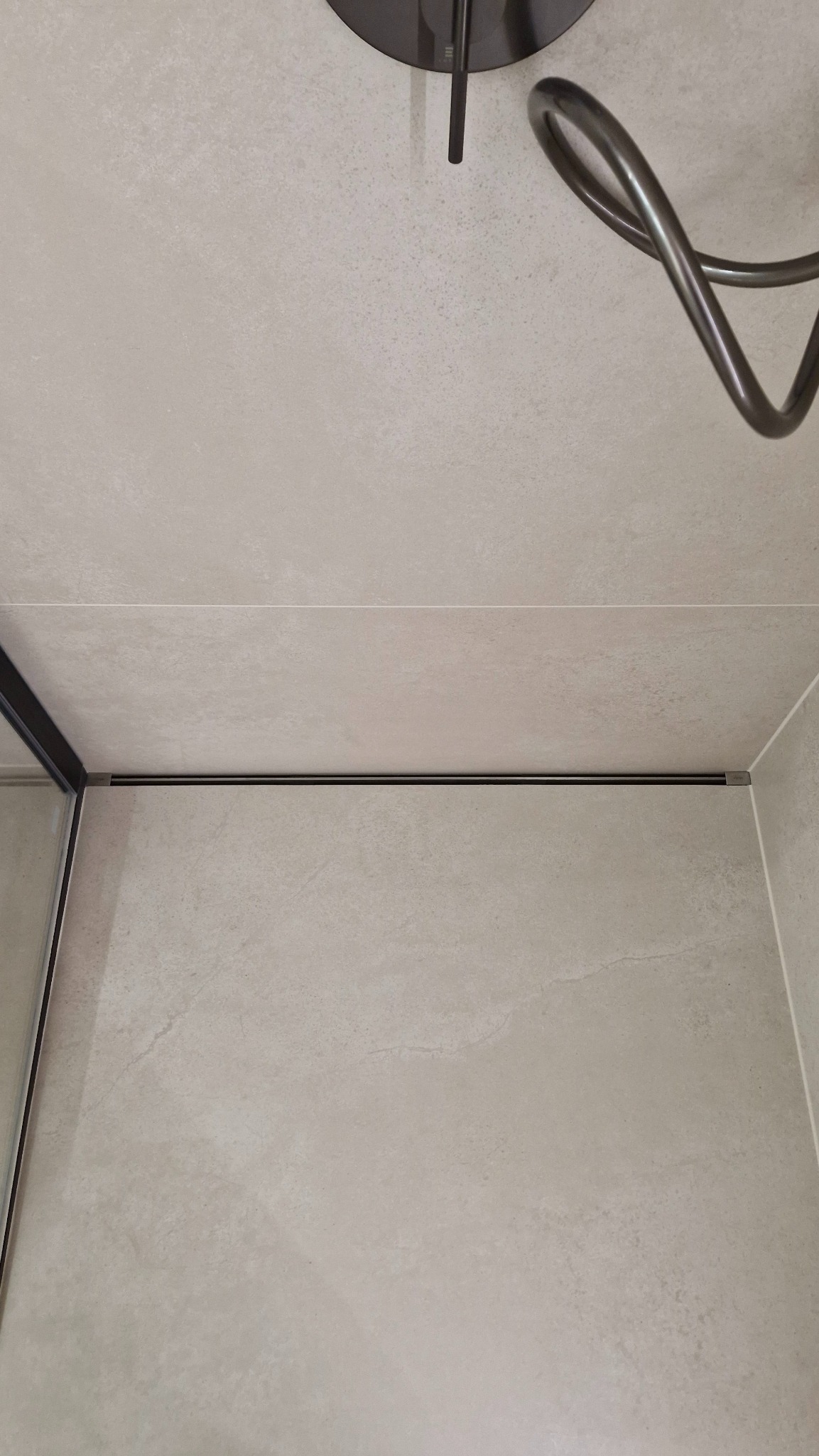 Beżowe płytki w kabinie prysznicowej z odpływem liniowym i deszczownicą w Świdnicy. Minimalistyczny design, neutralna kolorystyka, widok z góry.