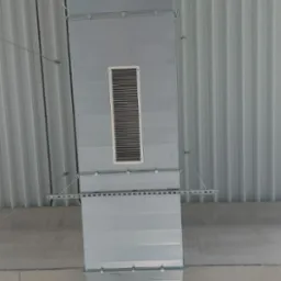 Szary kanał wentylacyjny prostokątny z kratką, zamocowany pod sufitem z blachy trapezowej, widok z dołu.