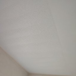 Sebastian Gajewski - Częściowo pomalowany sufit z widoczną fakturą, kontrastujący z gładką, świeżo pomalowaną powierzchnią, widoczne łączenie ścian i sufitu.