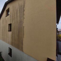 Maclin - Częściowo umyta elewacja budynku z widocznymi zaciekami i różnicą w kolorze przed i po czyszczeniu. Widoczne trzy okna na bocznej ścianie.