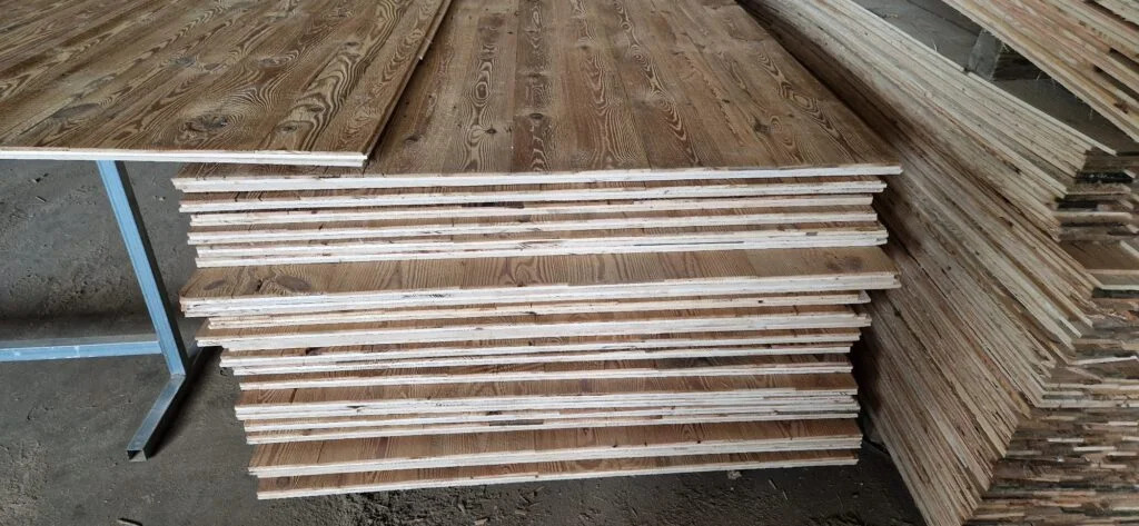 Stos ułożonych desek z widocznym rysunkiem słojów drewna, niektóre deski leżą na metalowym stelażu.