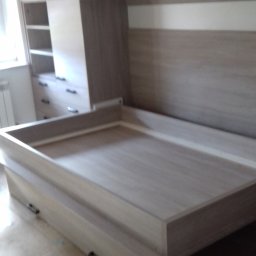 Ergo Meble - Beżowe meble do sypialni z szafkami wiszącymi i łóżkiem ze schowkami, widoczne szuflady i półki, minimalistyczny styl, oświetlenie dzienne.