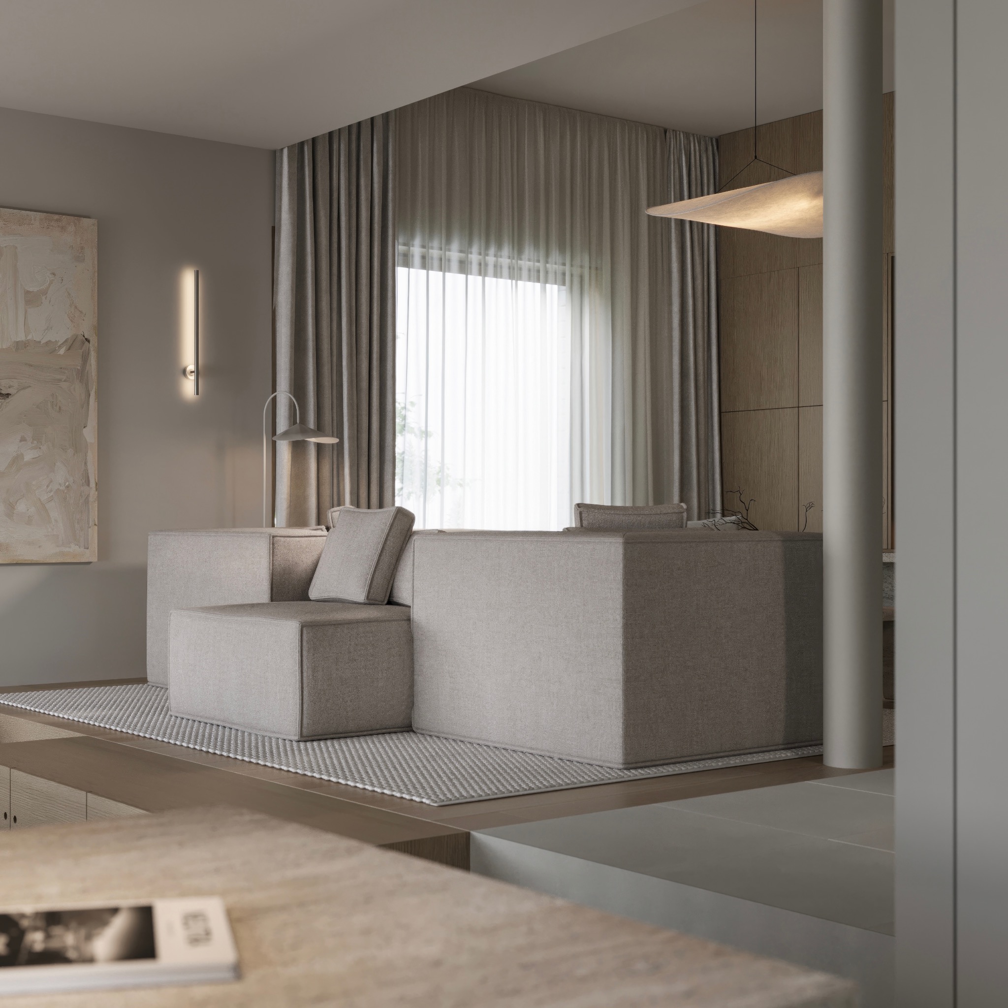Neutralna kolorystyka salonu z modułową sofą z szarej tkaniny, minimalistyczną lampą i abstrakcyjnym obrazem na ścianie, doświetlona naturalnym światłem przez okno z zasłonami.