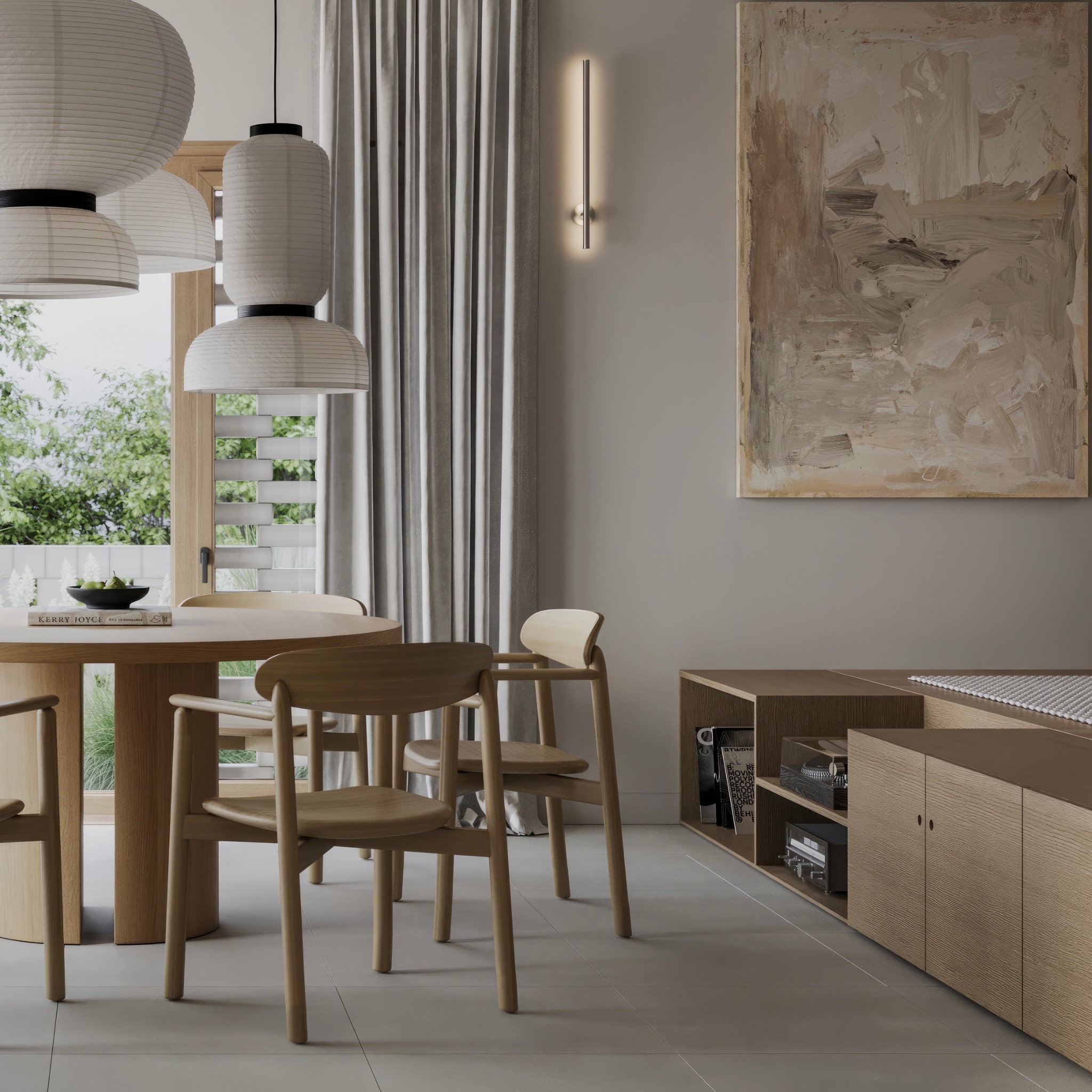 Jasna jadalnia z okrągłym drewnianym stołem, krzesłami o prostym designie, wiszącymi lampami w stylu japońskim i abstrakcyjnym obrazem na ścianie.