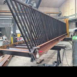 Bartosz Zając - Konstrukcja metalowa balustrady w warsztacie, widoczne spawy, uchwyty mocujące i narzędzia, surowy stan przed obróbką i malowaniem.