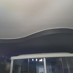 Krystian Gula - Kabina prysznicowa z przesuwnymi drzwiami w łazience w Grójcu, widoczny fragment sufitu z dekoracyjnym podwieszanym elementem.