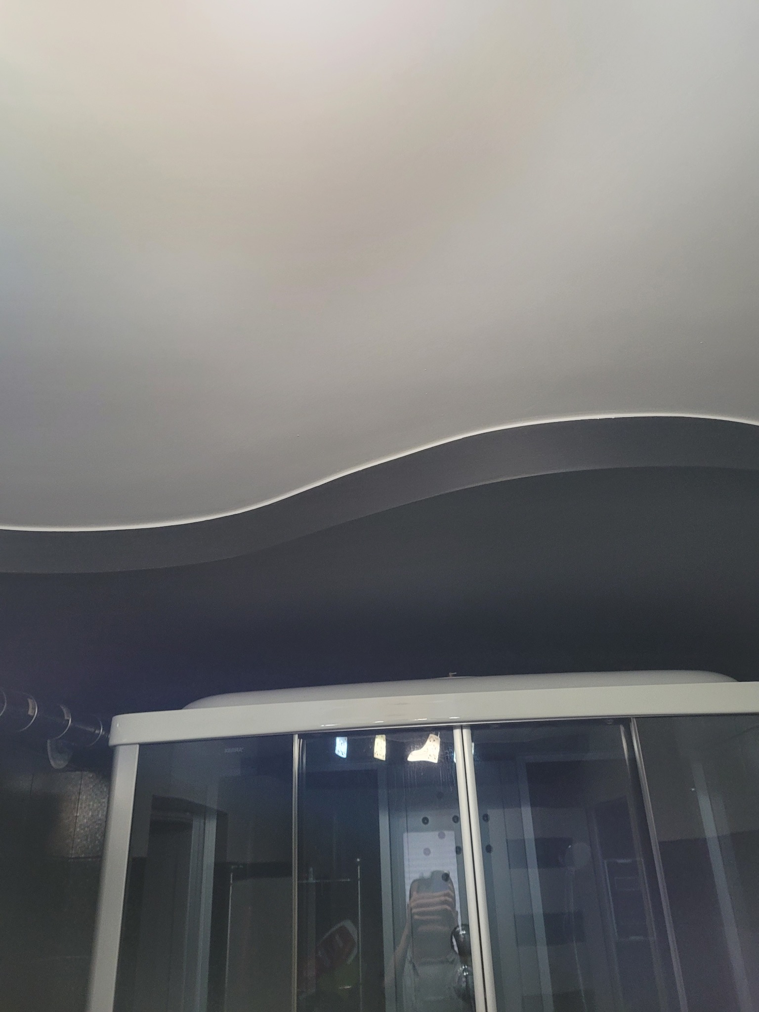 Kabina prysznicowa z przesuwnymi drzwiami w łazience w Grójcu, widoczny fragment sufitu z dekoracyjnym podwieszanym elementem.