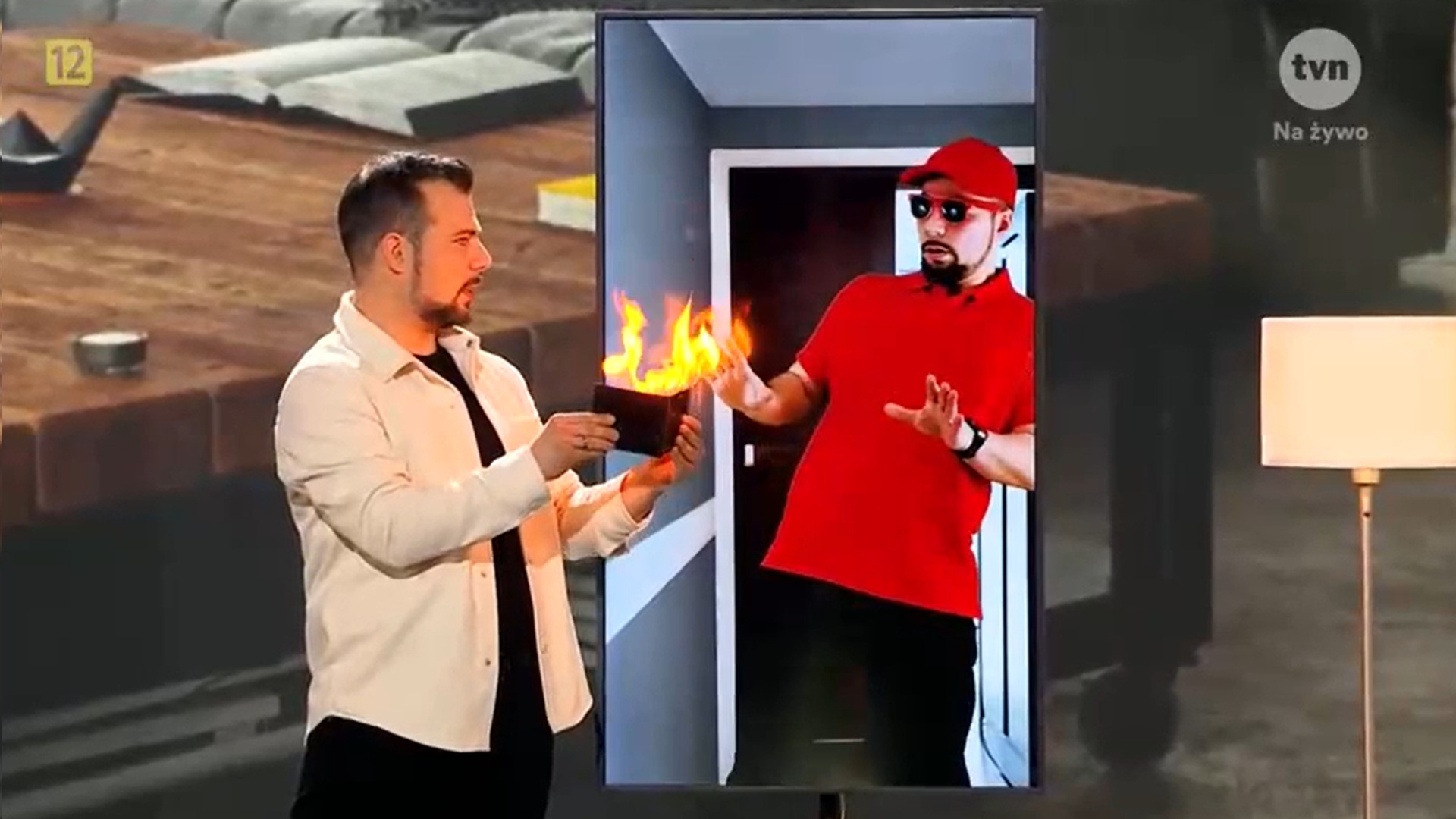 Iluzjonista prezentuje płonący portfel na scenie programu Mam Talent 2024, drugi iluzjonista w czerwonym stroju obserwuje z ekranu.
