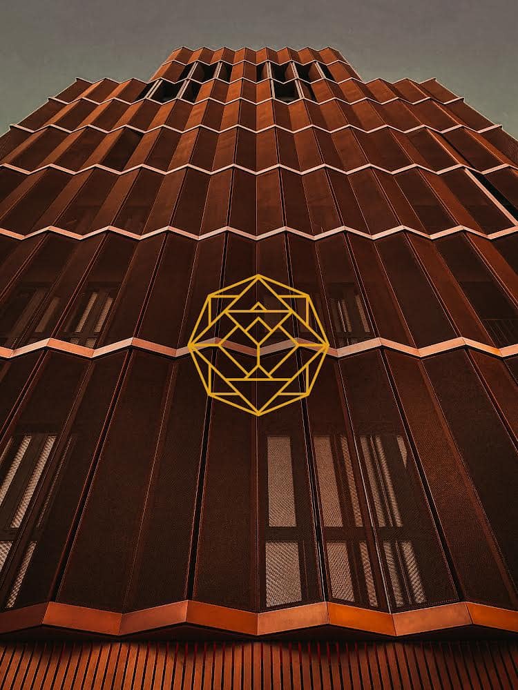 Fasada budynku z metalowymi panelami w odcieniach brązu i miedzianymi akcentami, widziana z dołu, z nałożonym geometrycznym logo w kolorze złotym.