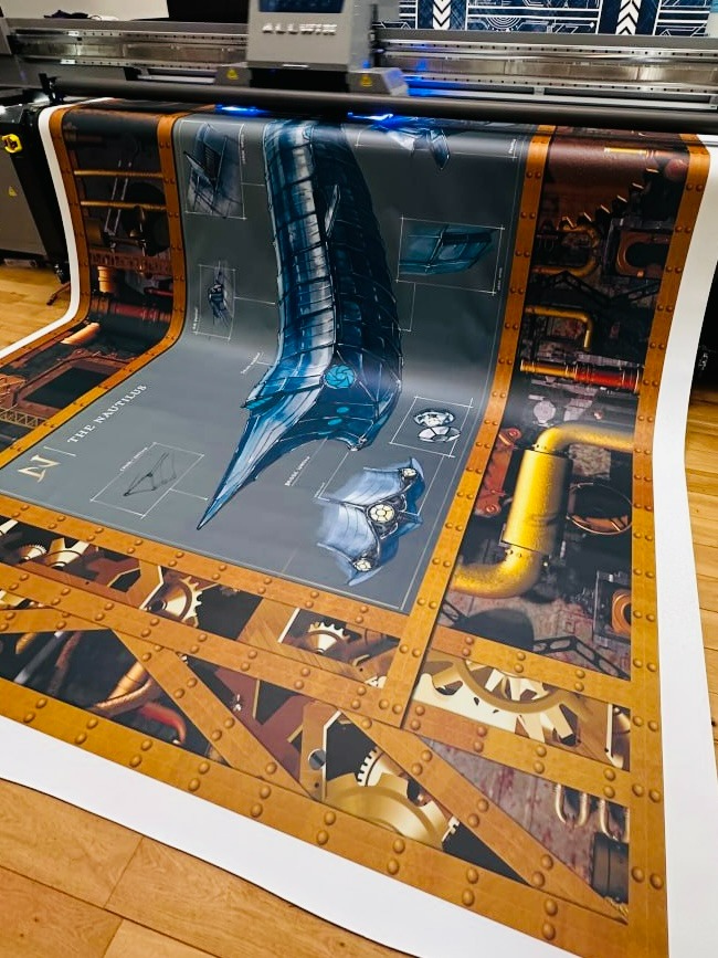 Wydruk wielkoformatowy z ilustracją steampunkowego okrętu podwodnego 'The Nautilus' w trakcie produkcji, widoczne elementy mechaniczne i plany techniczne.