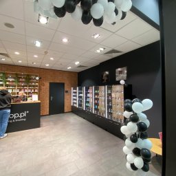 Twoja Ekipa Remontowa Konrad Lewicki - Nowoczesne wnętrze sklepu z ceglaną ścianą i czarnymi meblami, udekorowane białymi i czarnymi balonami. Widoczne regały z produktami i lada obsługi klienta.