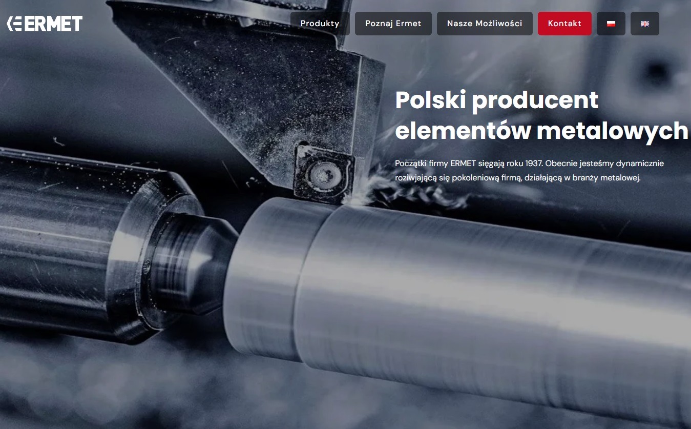 Metalowy wałek obrabiany na tokarce, wióry metalu widoczne w miejscu obróbki, logo firmy ERMET w tle.