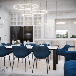 Sebastian Filuś - Wnętrze jadalni z niebieskimi krzesłami velvet, marmurowym stołem, oświetleniem pierścieniowym i kominkiem w tle, widok z salonu.