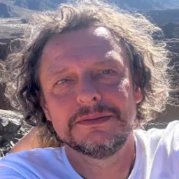 Autoportret elektryka z Warszawy na tle górskim, wykonany w słoneczny dzień.