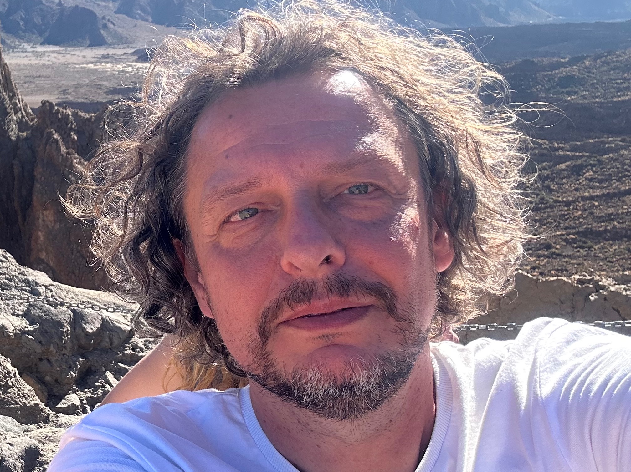 Autoportret elektryka z Warszawy na tle górskim, wykonany w słoneczny dzień.