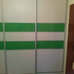 Sylwester Górski - Dwudrzwiowa szafa przesuwna z białymi i zielonymi poziomymi pasami, widoczna podłoga z paneli i fragment brązowych drzwi.