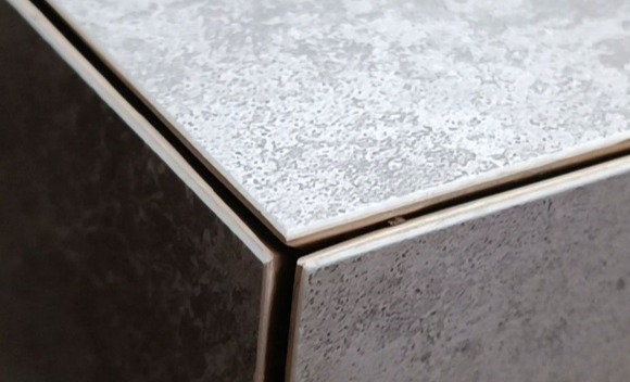 Szczegółowe zbliżenie na połączenie płytek pod kątem, ukazujące szarą i białą teksturę oraz delikatne szczeliny między nimi.