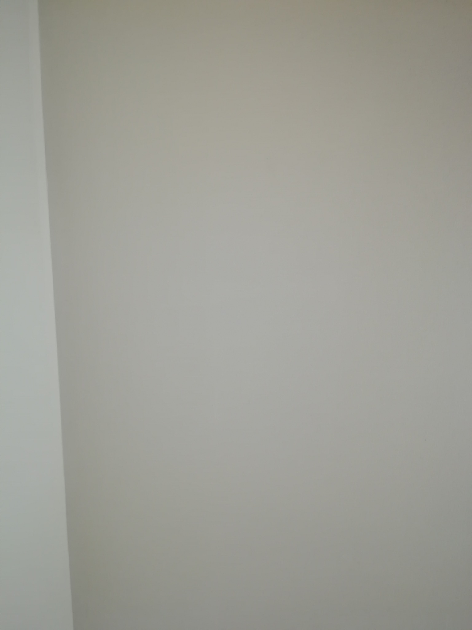 Świeżo pomalowana, gładka ściana w odcieniu jasnego beżu, widoczny fragment narożnika.