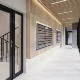 Korytarz z drewnianą boazerią i skrzynkami pocztowymi w nowoczesnym budynku w Łodzi. Widoczne schody i drzwi z czarnymi ramami.