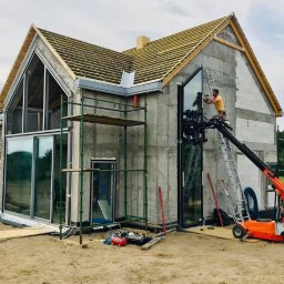 PAWEŁ KRAUSE Krause Expert - Montaż dużego, panoramicznego okna w surowym stanie domu jednorodzinnego przy użyciu specjalistycznego dźwigu próżniowego i rusztowań.