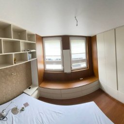 Serhii Hubrii SH ART - Pokój z łóżkiem, zabudową szaf i półek w jasnych odcieniach, z siedziskiem przy oknie i drewnianą podłogą.