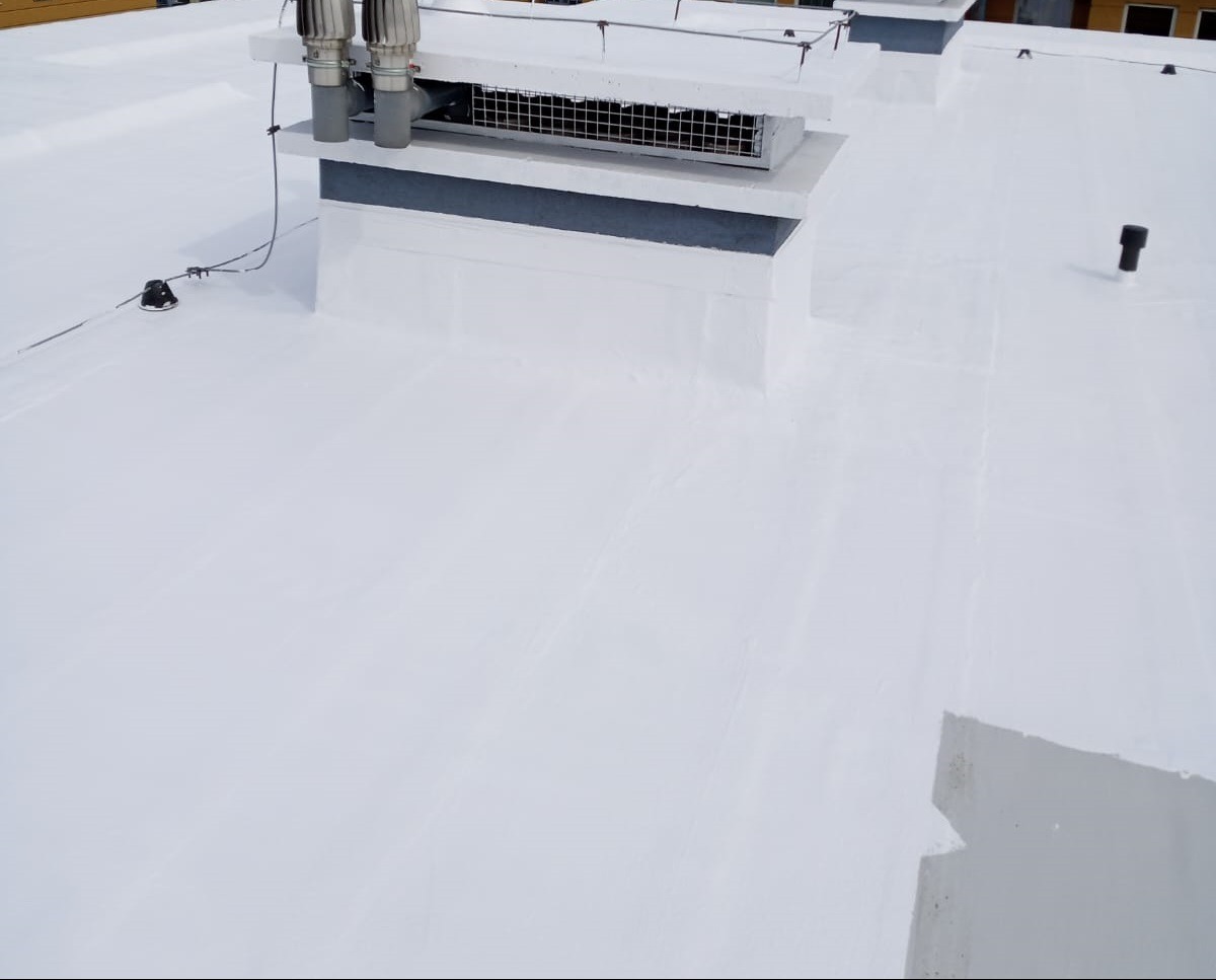 Biały dach płaski po renowacji z widocznymi kominami wentylacyjnymi i anteną.