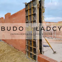 Wznoszenie ściany z czerwonej cegły ceramicznej z użyciem szalunków systemowych, widoczny żuraw budowlany w tle.