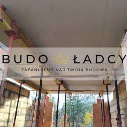 Budowładcy sp. z o.o. - Wnętrze budynku w trakcie budowy, widoczne ściany z pustaków ceramicznych, podpory stropowe i szalunek stropu, na pierwszym planie logo firmy budowlanej.