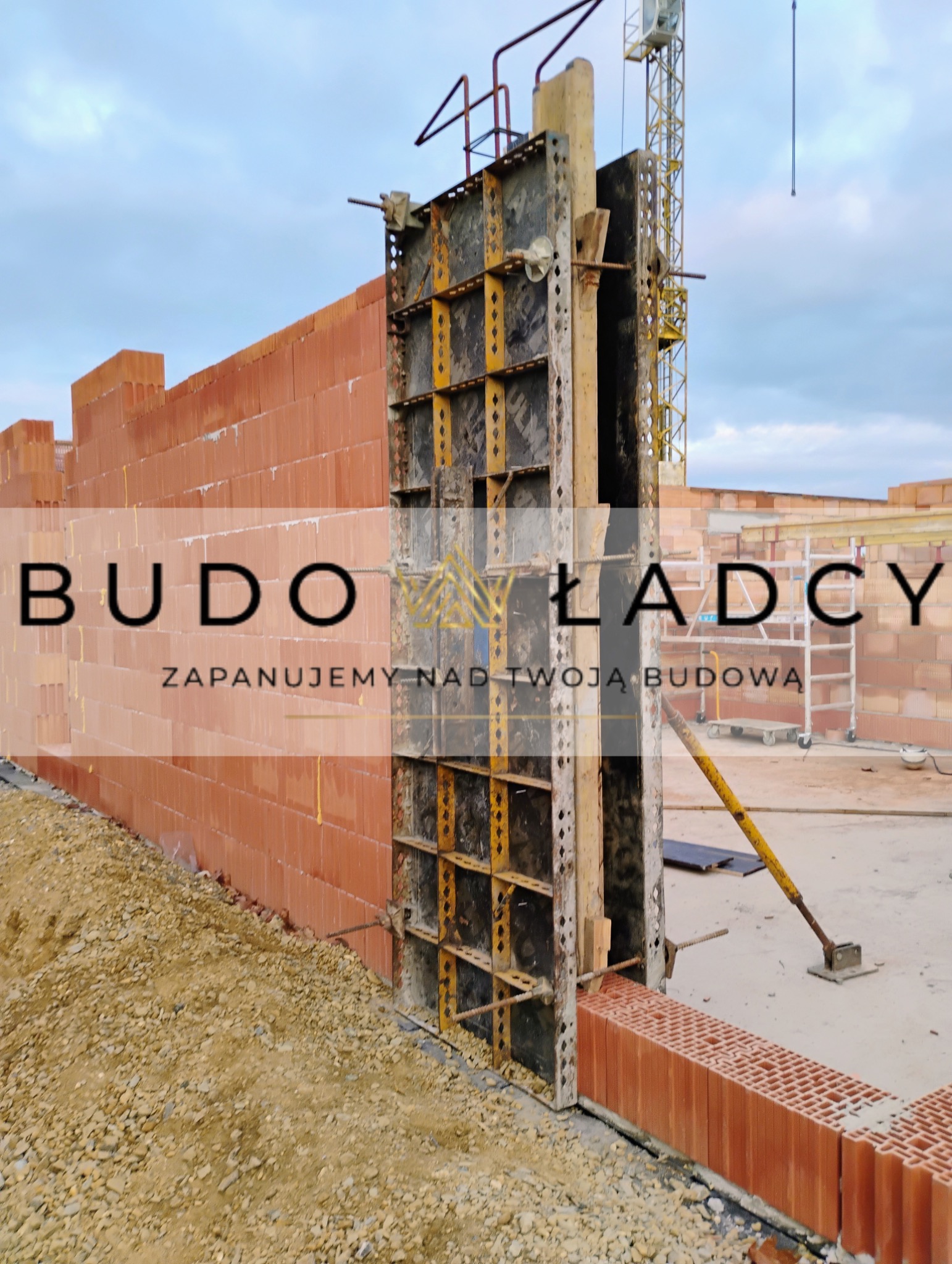 Wznoszenie ściany z czerwonej cegły ceramicznej z użyciem szalunków systemowych, widoczny żuraw budowlany w tle.