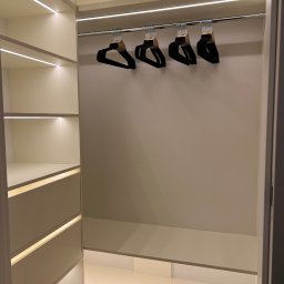 Frans meble - Wnętrze jasnej garderoby z oświetleniem LED, puste półki i wieszaki na ubrania