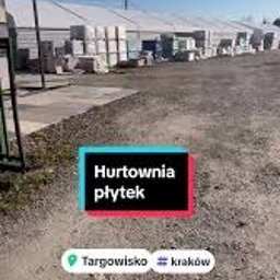 MAXI GRES - Hurtownia płytek budowlanych na zewnątrz, widoczne palety z materiałami pod zadaszeniem, w tle błękitne niebo.
