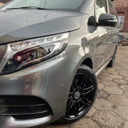 Detailing Olivier Marciniak - Szary Mercedes-Benz V-klasy z czarnymi felgami, pokryty kroplami wody, zaparkowany na brukowanej nawierzchni przed ceglanym budynkiem.