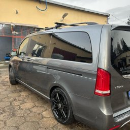 Detailing Olivier Marciniak - Szary Mercedes V300d z relingami dachowymi po myciu, mokry lakier i czarne felgi na tle żółtej ściany myjni.