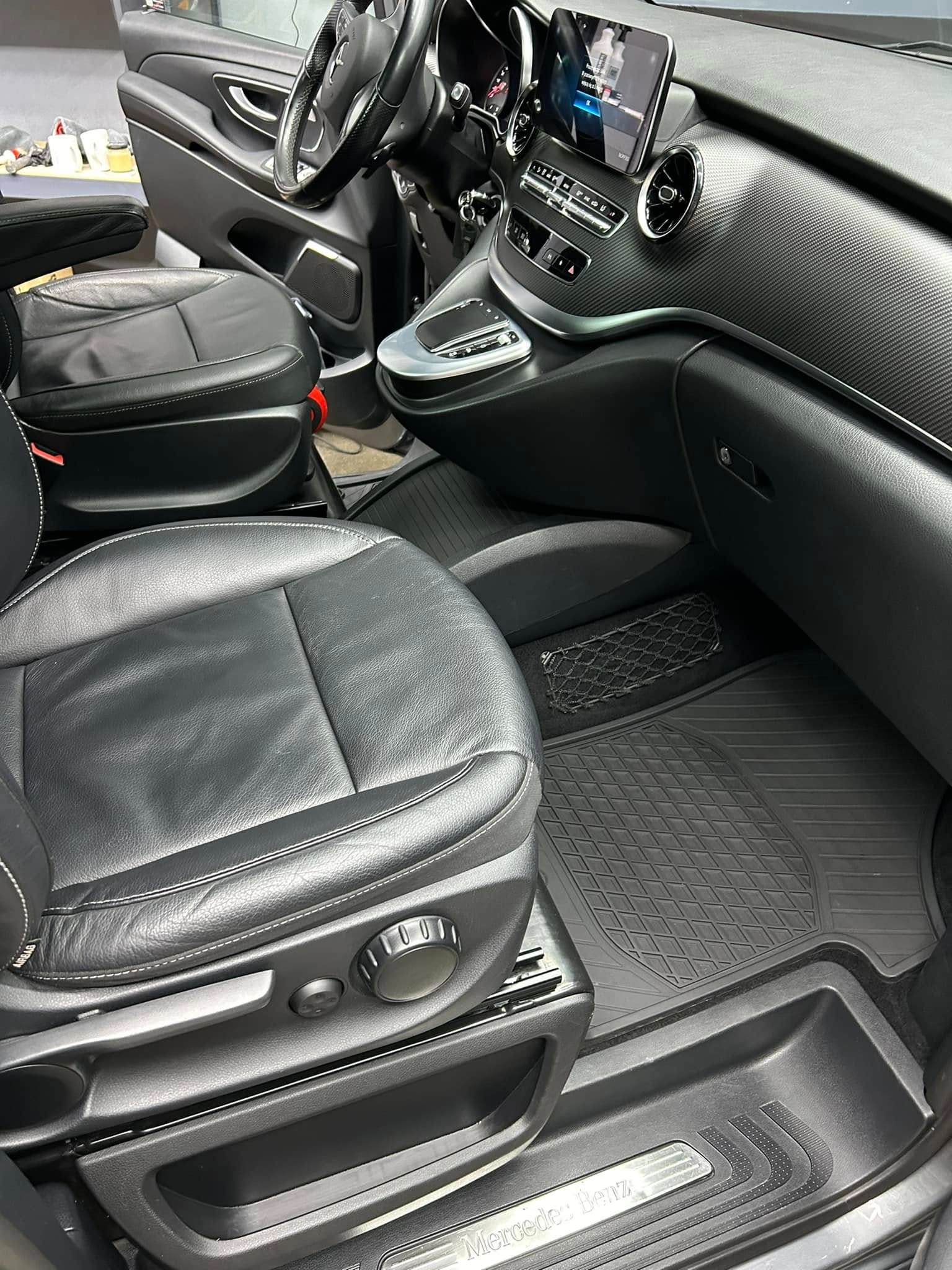 Wnętrze samochodu Mercedes-Benz V-klasa po czyszczeniu: czarne skórzane fotele z białymi przeszyciami, gumowe dywaniki w romby i deska rozdzielcza z fakturą włókna węglowego.
