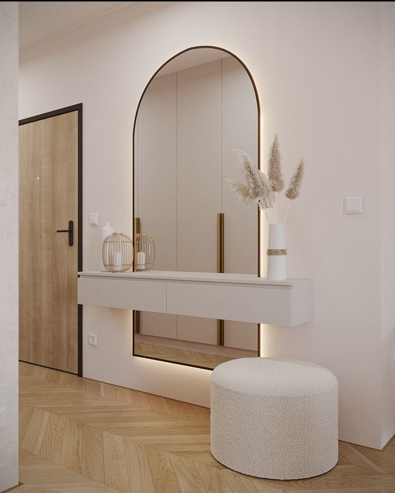 Nowoczesny przedpokój z oświetlonym lustrem w kształcie łuku, minimalistyczną konsolą z szufladami, dekoracyjnymi lampionami i puszystym pufem na parkiecie w jodełkę.