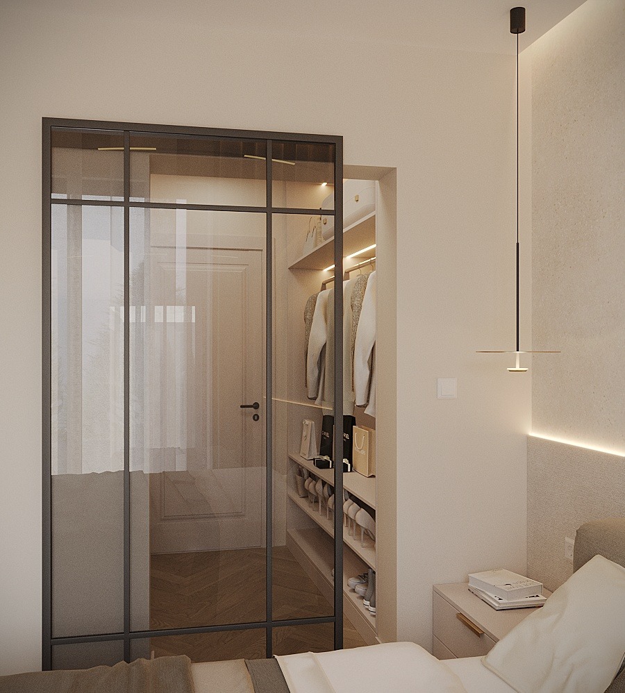 Sypialnia z przeszkloną garderobą w ciemnej ramie, widoczne ubrania i buty na półkach, minimalistyczna lampa wisząca, beżowe ściany i pościel.