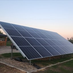 Nowoczesne technologie oze - Instalacja paneli słonecznych w Lublinie, widok na dom z werandą w tle, wieczorny krajobraz.