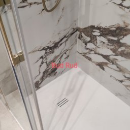 Bud Rud - Nowoczesna kabina prysznicowa z marmurowymi panelami ściennymi i złotą armaturą, widoczny odpływ liniowy.